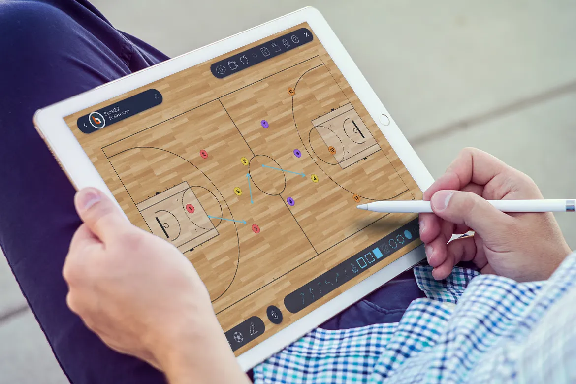 Entrenador de baloncesto diseñando una jugada con el lápiz sobre la pizarra táctica de Bcoach en una tablet